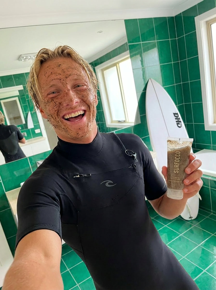 Surfer holding Surfocco face scrub on beach natural surf skincare for surfers